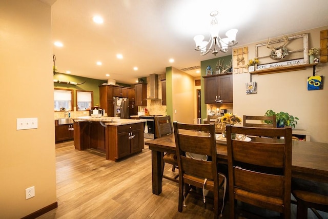 dining room featuring an inviting chandelier, sink, and light hardwood / wood-style flooring