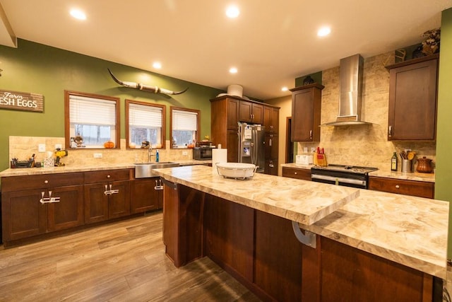 kitchen featuring wood counters, wall chimney exhaust hood, stainless steel appliances, sink, and light hardwood / wood-style floors