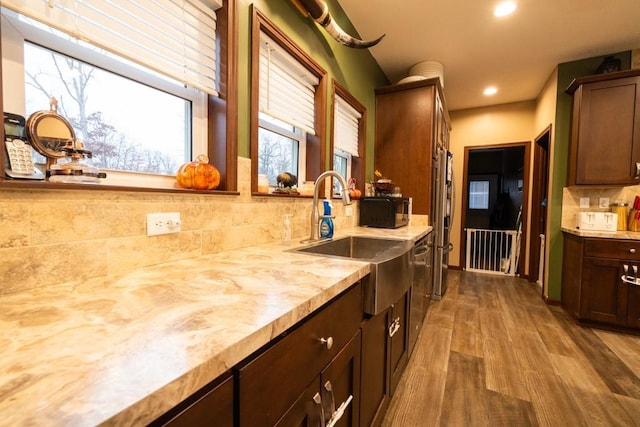 kitchen featuring tasteful backsplash, sink, wood-type flooring, and dark brown cabinets