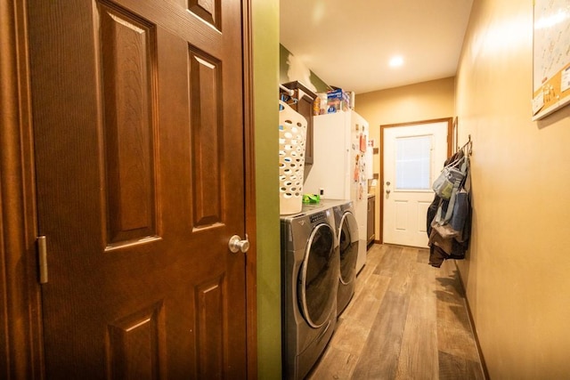 laundry room with cabinets, light hardwood / wood-style flooring, and washing machine and clothes dryer