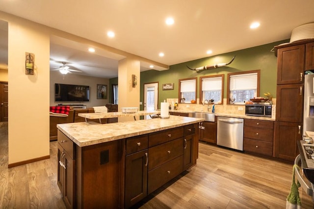 kitchen featuring a center island, sink, light hardwood / wood-style flooring, ceiling fan, and stainless steel appliances