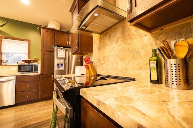 kitchen featuring butcher block countertops, light hardwood / wood-style floors, stainless steel appliances, and ventilation hood