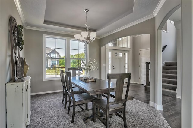 dining area with a tray ceiling, dark hardwood / wood-style flooring, and an inviting chandelier