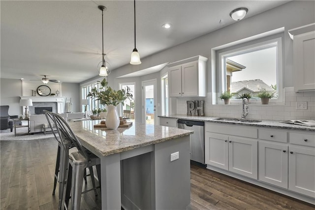 kitchen with dishwasher, tasteful backsplash, decorative light fixtures, a kitchen island, and white cabinetry