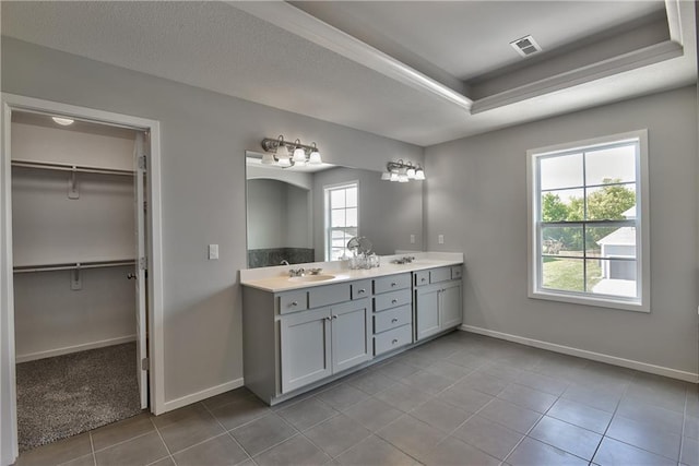 bathroom with tile patterned floors, a raised ceiling, and vanity