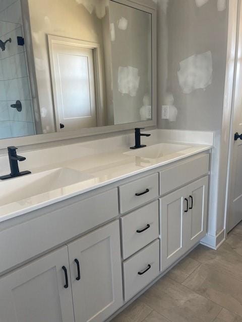 full bath featuring a sink, double vanity, and a tile shower