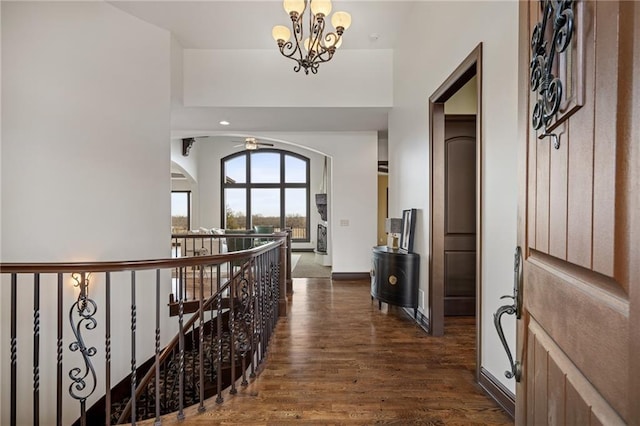 corridor with dark wood-type flooring and a chandelier