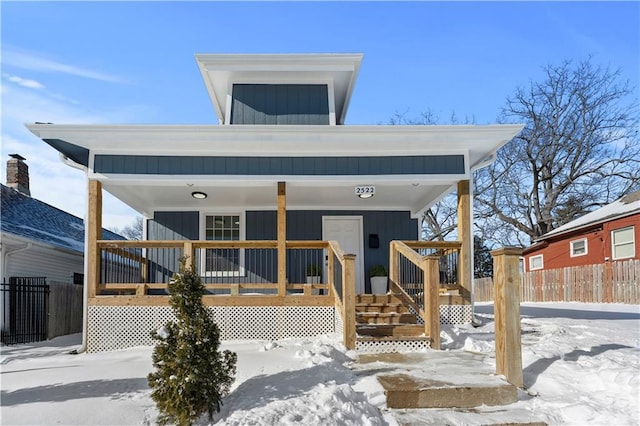 snow covered rear of property featuring a porch