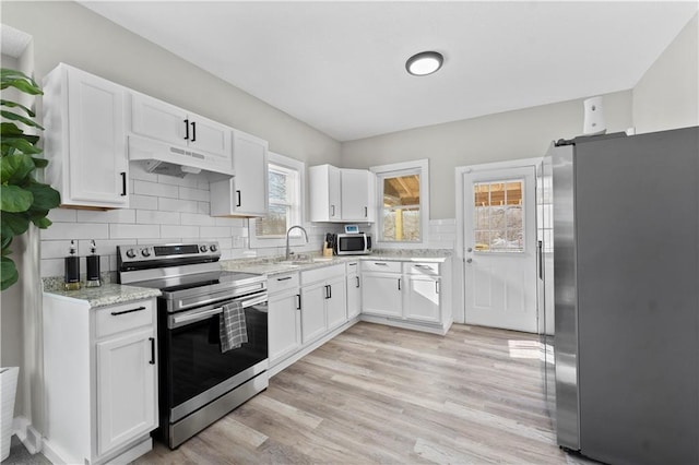 kitchen with white cabinets, sink, decorative backsplash, light stone countertops, and stainless steel appliances