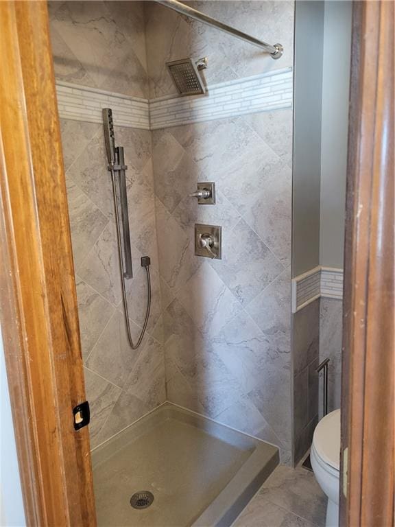 bathroom with a tile shower and toilet