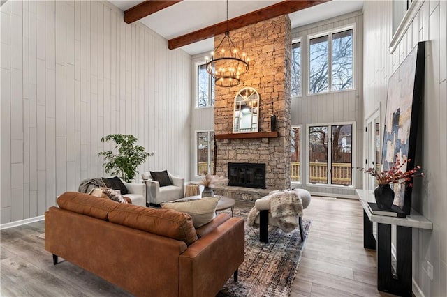 living room with hardwood / wood-style floors, a towering ceiling, a fireplace, and beamed ceiling