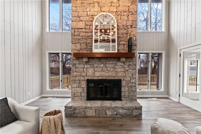 living room with a fireplace, a chandelier, wood-type flooring, and a high ceiling