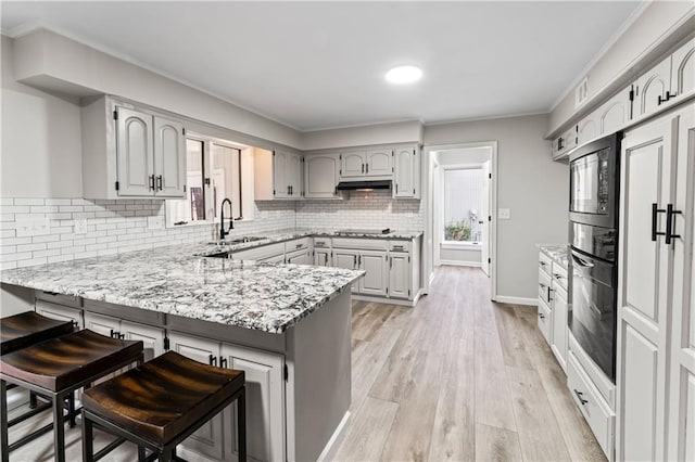 kitchen with sink, a breakfast bar area, gray cabinetry, kitchen peninsula, and black appliances