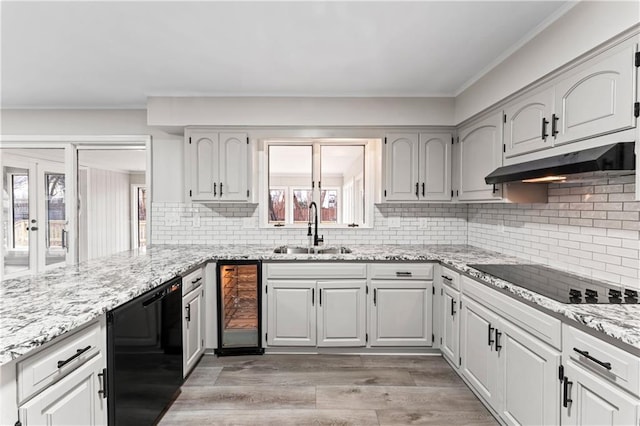 kitchen with sink, light stone countertops, light hardwood / wood-style floors, black electric cooktop, and beverage cooler