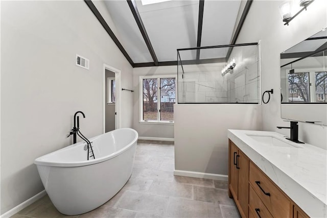 bathroom featuring vanity, a tub to relax in, and vaulted ceiling