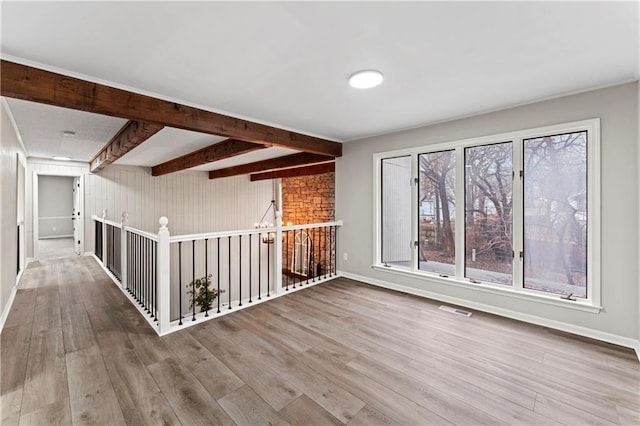 unfurnished room with hardwood / wood-style flooring and beam ceiling