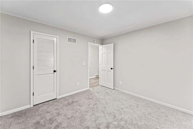 unfurnished bedroom with crown molding and light colored carpet