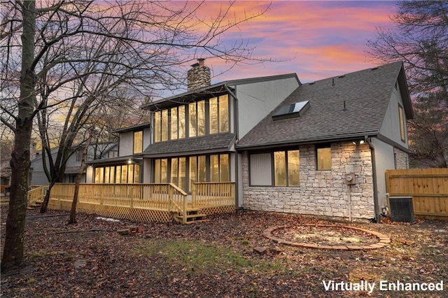 back house at dusk with central AC unit and a deck