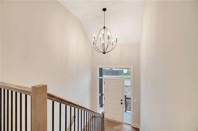 foyer entrance featuring high vaulted ceiling, wood finished floors, and an inviting chandelier
