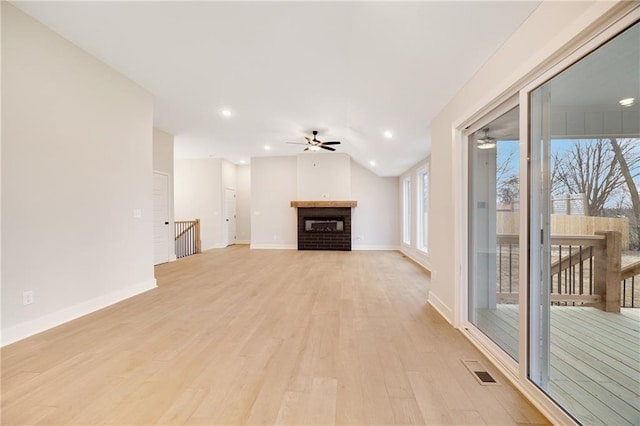 unfurnished living room with visible vents, baseboards, light wood-type flooring, a brick fireplace, and a ceiling fan