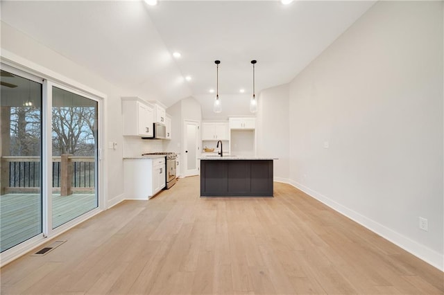 kitchen with lofted ceiling, white cabinetry, baseboards, stainless steel gas range oven, and light wood finished floors