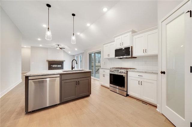 kitchen featuring a sink, light wood-style floors, backsplash, white cabinetry, and appliances with stainless steel finishes