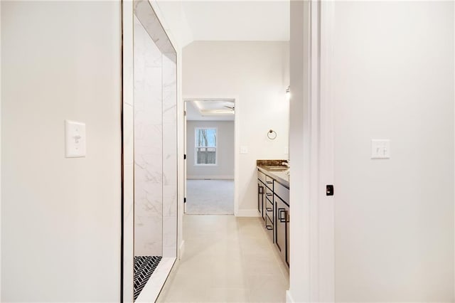 hallway featuring lofted ceiling and baseboards