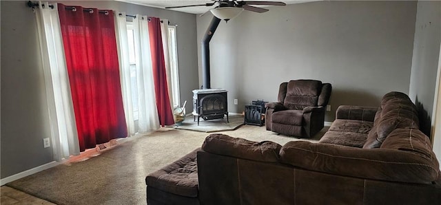 carpeted living room with ceiling fan and a wood stove