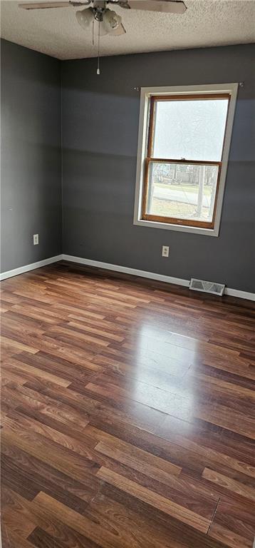 unfurnished room with ceiling fan, dark hardwood / wood-style floors, and a textured ceiling