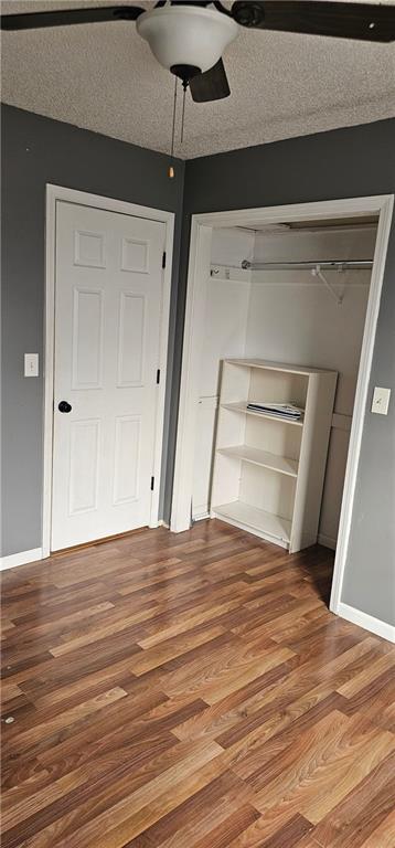 unfurnished bedroom featuring wood-type flooring, ceiling fan, a textured ceiling, and a closet