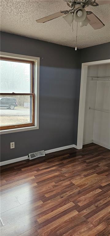 unfurnished bedroom with dark hardwood / wood-style floors, a textured ceiling, and a closet