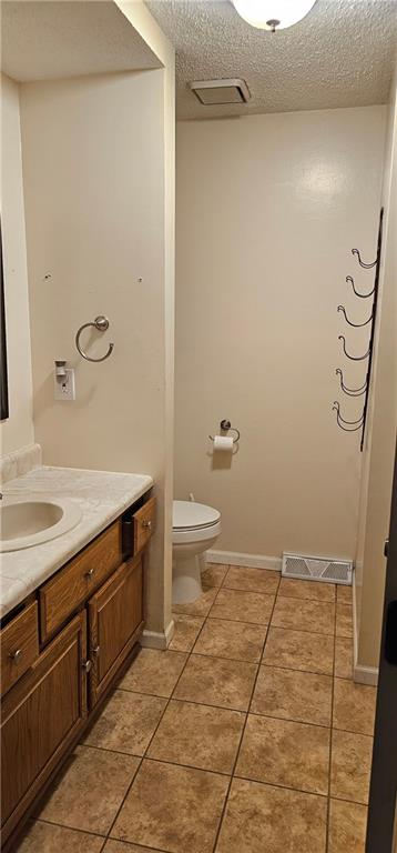 bathroom with tile patterned floors, vanity, toilet, and a textured ceiling