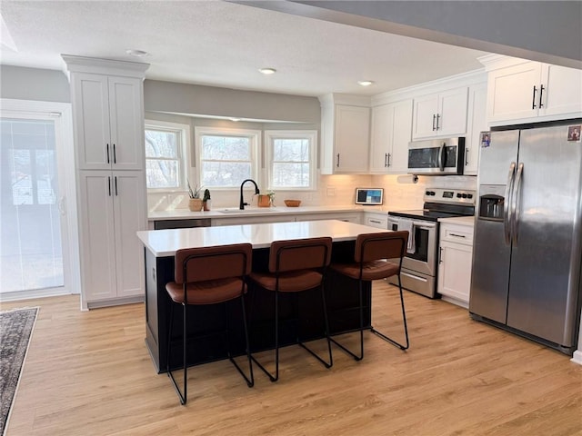 kitchen with a kitchen bar, sink, white cabinetry, and stainless steel appliances