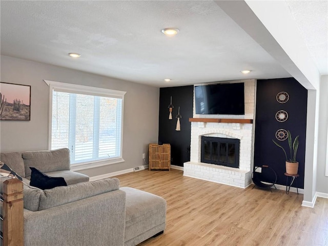 living room featuring wood-type flooring and a brick fireplace