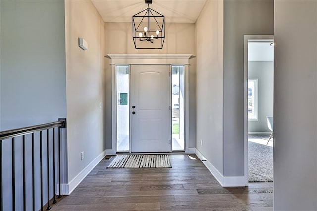entryway with baseboards, dark wood-type flooring, and a chandelier