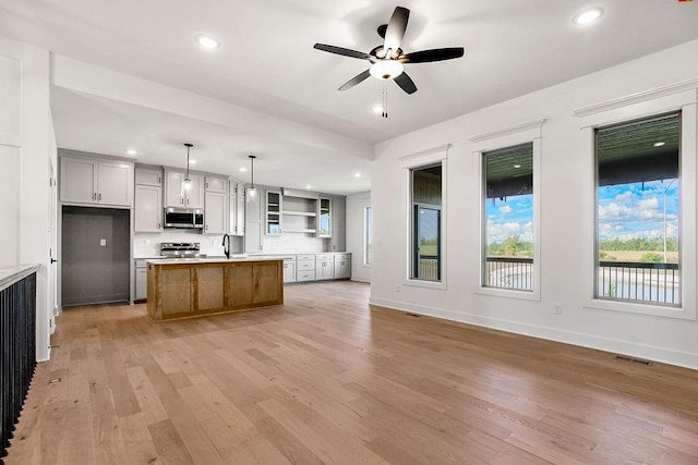 kitchen featuring a center island, hanging light fixtures, appliances with stainless steel finishes, and light hardwood / wood-style flooring