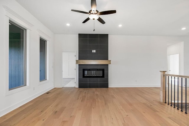 unfurnished living room featuring ceiling fan, light wood-type flooring, and a tiled fireplace