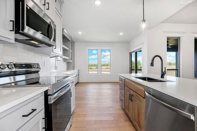 kitchen featuring white cabinets, appliances with stainless steel finishes, pendant lighting, and sink