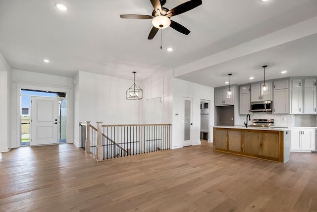 kitchen featuring appliances with stainless steel finishes, sink, a center island, white cabinetry, and hanging light fixtures