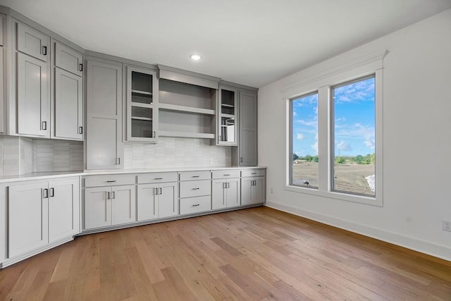 kitchen with tasteful backsplash, gray cabinetry, and light hardwood / wood-style flooring