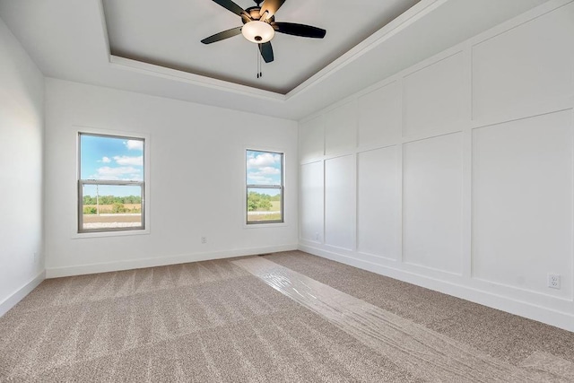 empty room with carpet, a raised ceiling, and ceiling fan