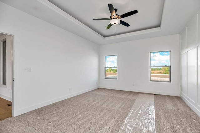 carpeted empty room featuring a tray ceiling and ceiling fan