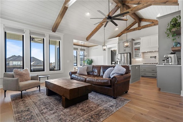 living room with vaulted ceiling with beams, wood ceiling, ceiling fan with notable chandelier, and hardwood / wood-style floors