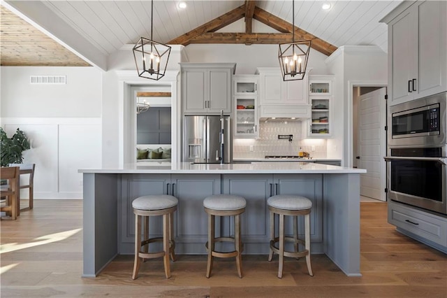 kitchen featuring decorative light fixtures, a large island, stainless steel appliances, and lofted ceiling with beams