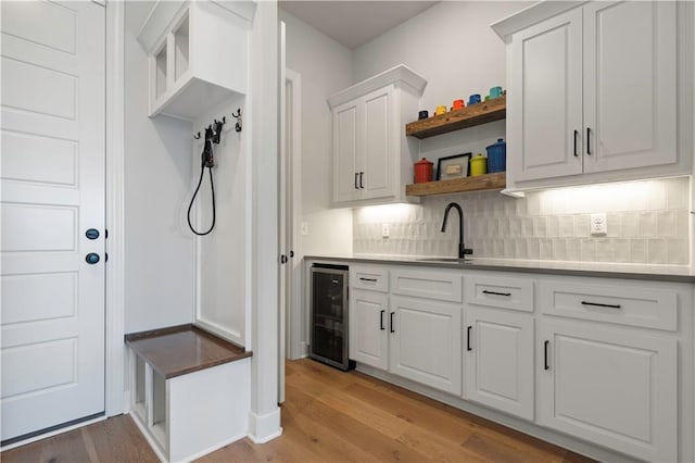 mudroom with light wood-type flooring, sink, and beverage cooler