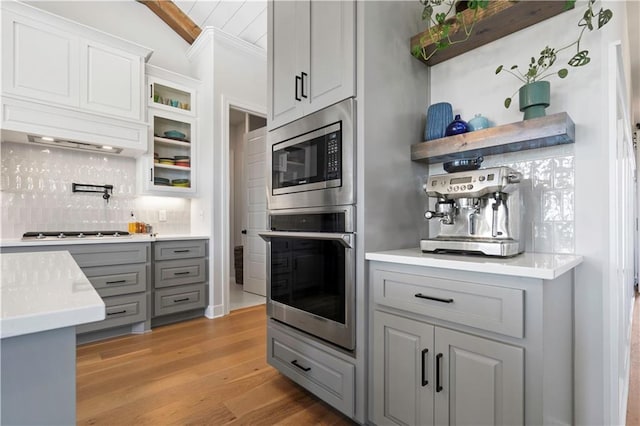 kitchen with light wood-type flooring, appliances with stainless steel finishes, tasteful backsplash, and gray cabinets