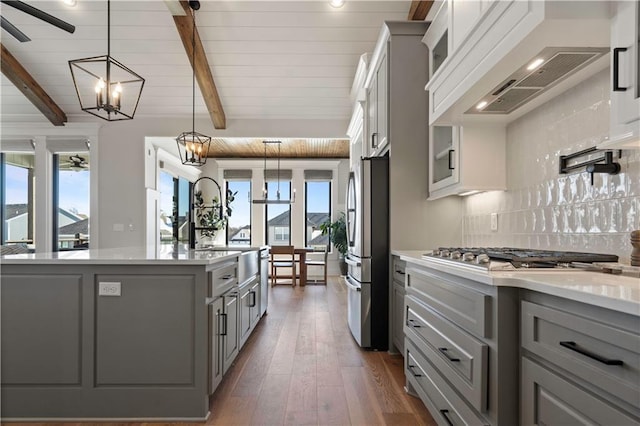 kitchen with appliances with stainless steel finishes, decorative backsplash, hanging light fixtures, gray cabinetry, and custom range hood