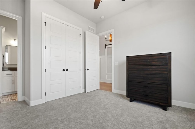 unfurnished bedroom featuring ceiling fan, connected bathroom, a closet, and light carpet