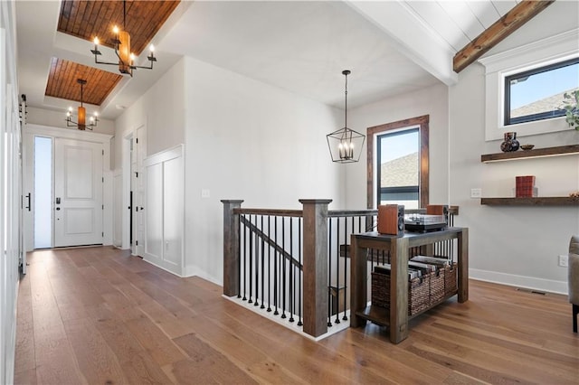 corridor featuring plenty of natural light, a chandelier, hardwood / wood-style floors, and beamed ceiling