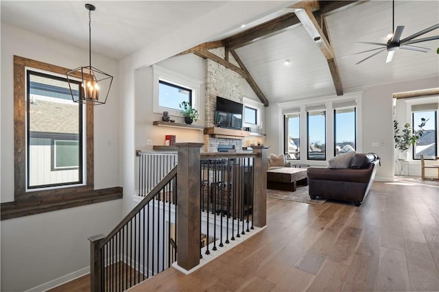 living room with lofted ceiling with beams, a fireplace, ceiling fan with notable chandelier, and hardwood / wood-style flooring